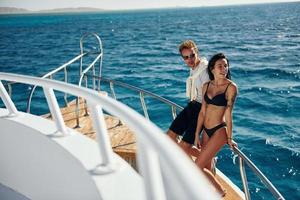 Cheerful young couple standing on the yacht on the sea. Conception of vacation photo