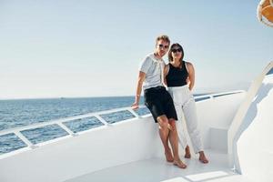 Cheerful young couple standing on the yacht on the sea. Conception of vacation photo