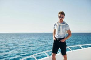 Young male tourist is on the yacht on the sea. Conception of vacation photo