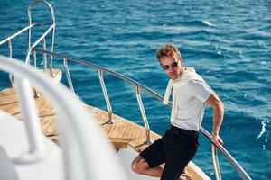 Posing for a camera. Young male tourist is on the yacht on the sea. Conception of vacation photo