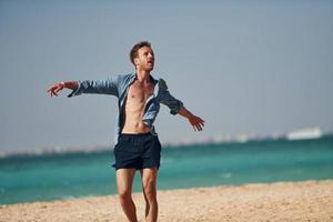 divirtiéndose. joven europeo tiene vacaciones y disfruta del tiempo libre en la playa del mar foto