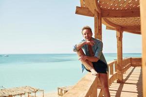 Wooden building. Young european man have vacation and enjoying free time on the beach of sea photo