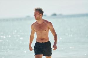 agua clara. joven europeo tiene vacaciones y disfruta del tiempo libre en la playa del mar foto