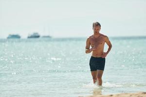 Clear water. Young european man have vacation and enjoying free time on the beach of sea photo