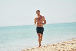 Clear water. Young european man have vacation and enjoying free time on the beach of sea photo