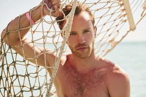 Warm weather. Young european man have vacation and enjoying free time on the beach of sea photo