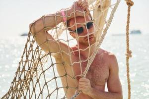 Warm weather. Young european man have vacation and enjoying free time on the beach of sea photo