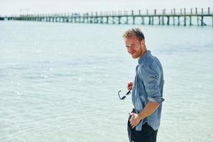 Clear water. Young european man have vacation and enjoying free time on the beach of sea photo