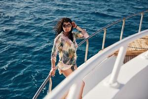 Mature woman standing on the yacht and enjoying her vacation on the sea photo