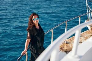 Mature woman standing on the yacht and enjoying her vacation on the sea photo