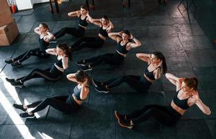 Doing abs. Group of young sportive people have crossfit day indoors in gym photo