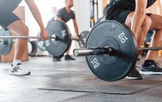 mediante el uso de pesos pesados. grupo de jóvenes deportistas tienen un día de crossfit en el interior del gimnasio foto