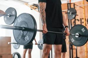 levantamiento de pesas. grupo de jóvenes deportistas tienen un día de crossfit en el interior del gimnasio foto