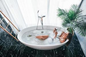 Top view. Beautiful young woman have free time at home in the bath photo