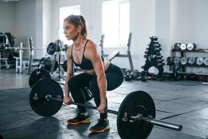 mujer joven fitness con tipo delgado de cuerpo haciendo ejercicios usando barra foto