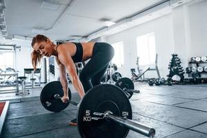 mujer joven fitness con tipo delgado de cuerpo haciendo ejercicios usando barra foto