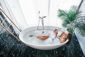 Top view. Beautiful young woman have free time at home in the bath photo