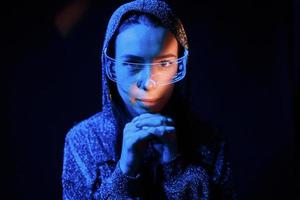 Portrait of young girl that is in eyeglasses in blue neon lighting photo