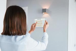 Rear view of woman that is indoors controlling smart home technology photo