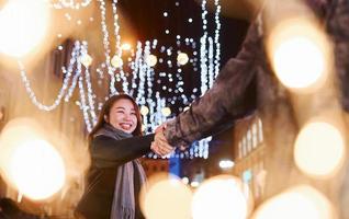 Artificial lighting by garlands. Happy multiracial couple together outdoors in the city celebrating New year photo