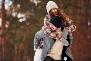 Cheerful couple have a walk in the winter forest at daytime photo