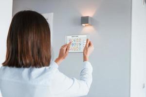 Rear view of woman that is indoors controlling smart home technology photo