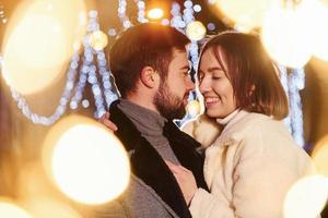 Embracing each other. Happy young couple celebrating New year outdoors on the street photo