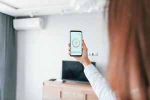 Rear view of woman that is indoors controlling smart home technology photo