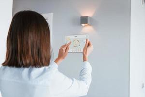 Rear view of woman that is indoors controlling smart home technology photo