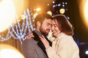 Embracing each other. Happy young couple celebrating New year outdoors on the street photo