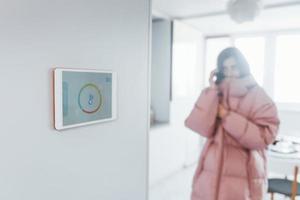 Problem with temperature. Woman is indoors controlling smart home technology photo