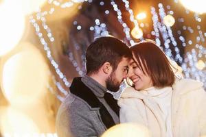 Embracing each other. Happy young couple celebrating New year outdoors on the street photo