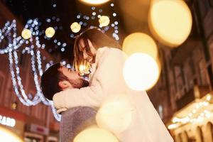 Embracing each other. Happy young couple celebrating New year outdoors on the street photo