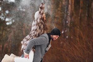 una pareja alegre da un paseo por el bosque de invierno durante el día foto