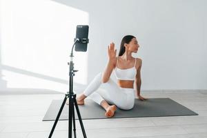 el teléfono está grabando video. joven mujer caucásica con forma de cuerpo delgado está en el interior durante el día foto