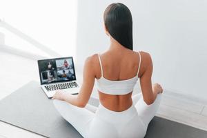 With laptop. Young caucasian woman with slim body shape is indoors at daytime photo