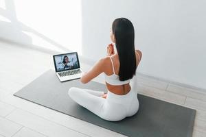 Online talking. Young caucasian woman with slim body shape is indoors at daytime photo