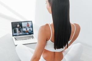 Online talking. Young caucasian woman with slim body shape is indoors at daytime photo