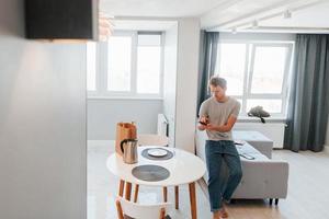 Young man in casual clothes is indoors controlling smart home technology photo