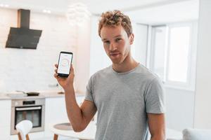 un joven con ropa informal está adentro controlando la tecnología del hogar inteligente foto