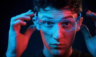 Close up portrait. Neon lighting. Young european man is in the dark studio photo