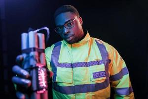 policía con bomba. iluminación de neón futurista. joven afroamericano en el estudio foto