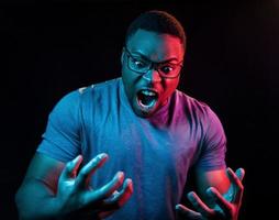 Facial expression. Futuristic neon lighting. Young african american man in the studio photo