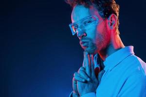 Neon lighting. Young european man is in the dark studio photo