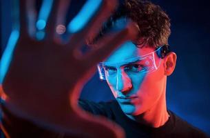 Close up portrait. Neon lighting. Young european man is in the dark studio photo