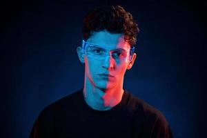 Close up portrait. Neon lighting. Young european man is in the dark studio photo