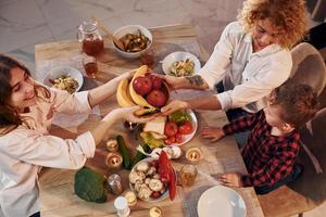 Cheerful people having happy weekend. Family of mother, daughter and son is on the kitchen at evening time photo