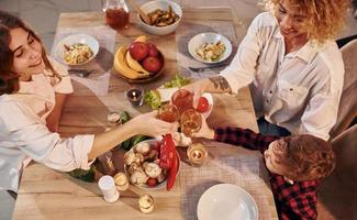 gente alegre teniendo feliz fin de semana. la familia de madre, hija e hijo está en la cocina por la noche foto