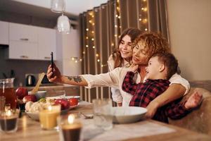 feliz familia de madre, hija e hijo está en la cocina por la noche foto