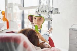 se mira en el espejo. niña visitando al dentista en la clínica. concepción de la estomatología foto